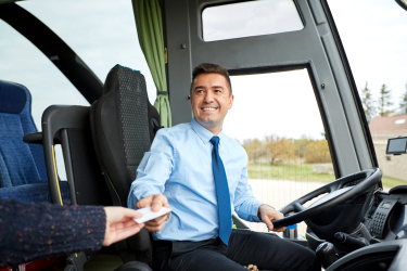 Usmiaty vodič autobusu podáva lístok cestujúcemu