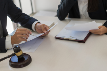Dvaja právnici prechádzajú dokumenty a na stole leží sudcovské kladívko