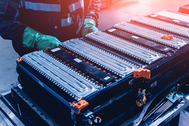 Človek s ochrannými pomôckami pri výrobe batérií