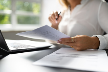 Žena kontroluje dokument pri notebooku