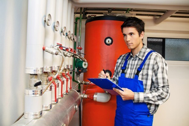 Muž kontroluje tlakové nádoby v kotolni